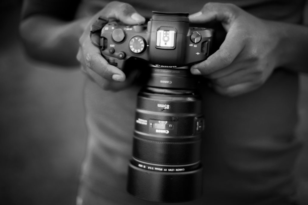 A man shown looking down at his camera while being held in his hands.